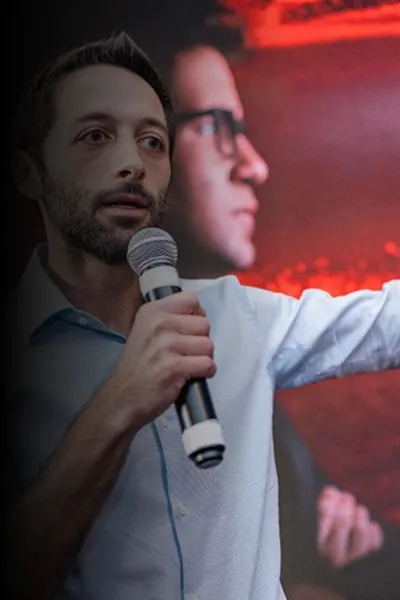 Yuri Busin falando no microfone em palestra